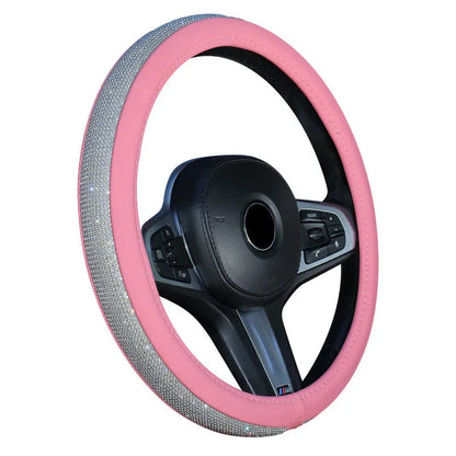 A pink steering wheel cover with silver rhinestone trim, shown fitted on a black multi-function steering wheel against a white background.